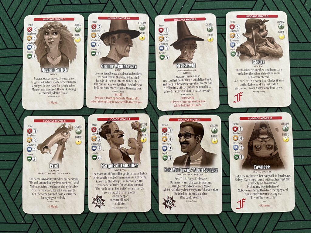 A photo of various volunteer cards from the Guards! Guards! board game, depicing Magrat Garlick, Granny Weatherwax, Mrs Earwig, Gladys (a Golem), Errol (a swamp dragon), the Maquis of Fantailer (a boxing fop), Moist von Lipwig/Albert Spangler (in a Groucho Marx style disguise) and Tawnee (an exotic dancer).