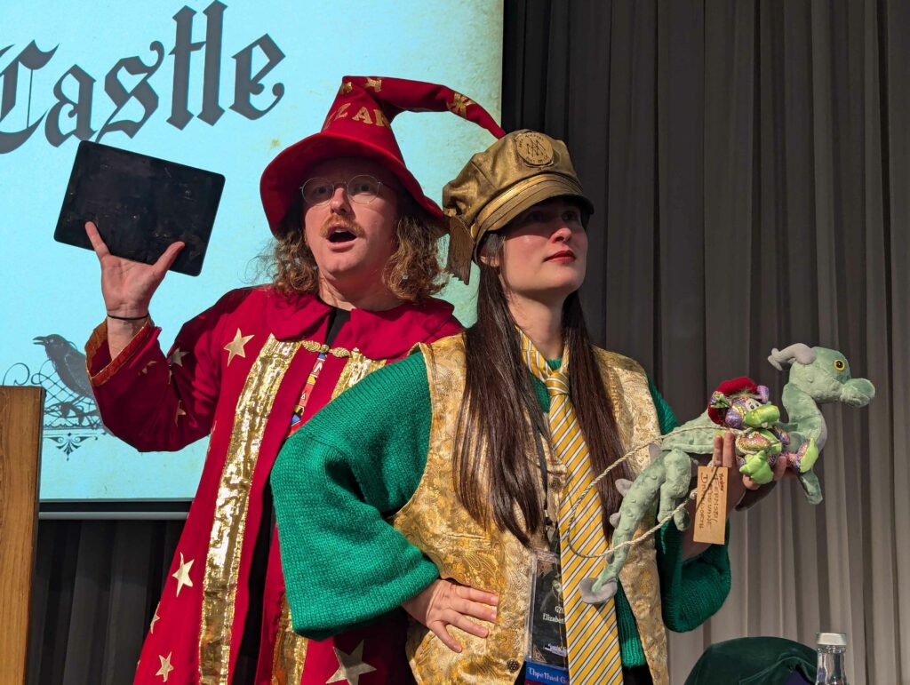 A photo of Ben and Liz, in costume as Rincewind and Moist von Lipwig, attempting to recreate the pose from the Pratchat logo.